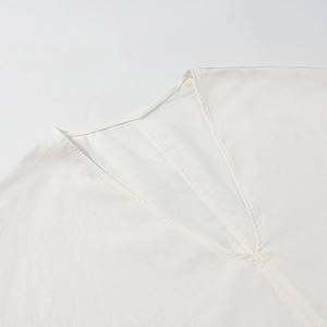 Macro detail of breathable off-white cotton linen fabric texture and elegant V-neckline seam