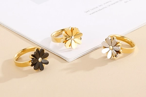 Detailed close-up of three daisy flower rings in gold, silver, and black finishes
