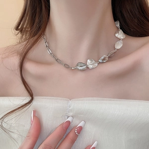 Primo piano di una collana in argento con perla barocca indossata da una modella elegante
