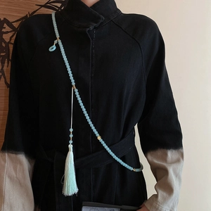Detail of elegant light blue glass bead tassel necklace styled on a black garment