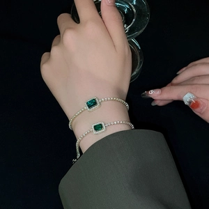 Close-up of emerald square zircon bracelet with diamond halo on silver chain for women