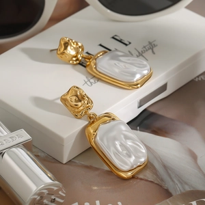 Baroque pearl drop earrings in gold setting displayed on a luxury fashion box