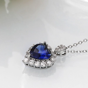 Detailed side view of heart-shaped sapphire blue pendant with halo diamond accents