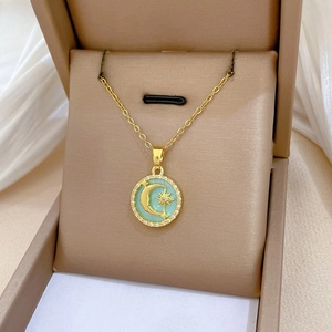 Macro shot of gold moon and star pendant necklace with cubic zirconia and shell inlay