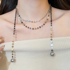Close-up of layered beaded necklace featuring silver sequins and grey pearl pendants