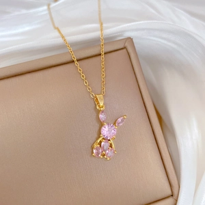 Close-up of pink rabbit pendant necklace with gold chain on silk background