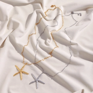 Detailed view of hammered starfish pendants in gold and silver on stainless steel chains