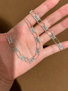 Macro detail of vintage silver hollow flower bracelet links held in hand for scale