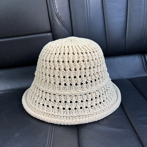 Detail of beige hollow knit bucket hat showing breathable mesh texture on a car seat