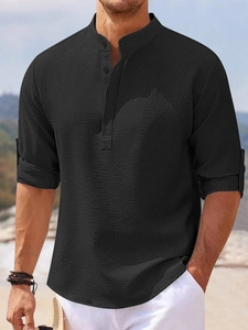 Detail of black waffle knit fabric on men's long sleeve polo shirt with buttoned collar
