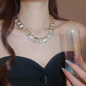 Close-up of luxury crystal necklace featuring square stones with sparkling tassels on a model