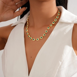 Close-up of vintage gold necklace with green gemstones worn on a female model