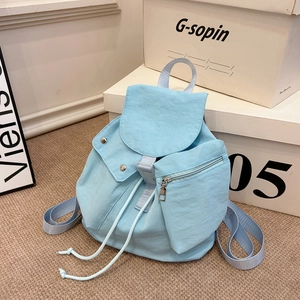 Detail of light blue nylon backpack featuring drawstring closure and front zipper pockets