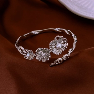 Detail of vintage silver bangle with twisted texture and pearl flower accents on velvet