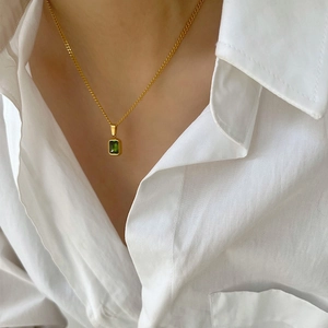 Detail of vintage emerald pendant necklace on model with elegant gold chain