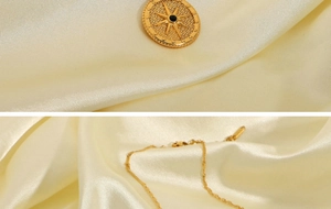 Detail of gold starburst pendant necklace with black center stone on silk background