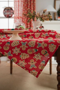 Close-up of festive gingerbread man and snowflake print on red cotton linen tablecloth