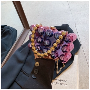 Detail of purple and gold acrylic bead evening bag with metallic chain on an open book
