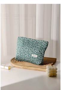 Close-up of green floral canvas makeup bag with H & R logo on a wooden tray