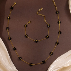 Detailed macro view of gold-tone stainless steel jewelry set with black flower beads
