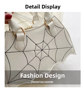 Close-up of white gothic bat bag with black spider web stitching and gold metal hardware