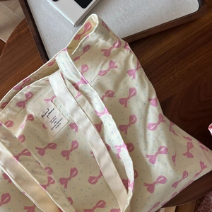 Détail d'un sac cabas en toile avec nœuds roses et pois bleus sur une table en bois