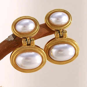 Close-up of 18K gold plated pearl earrings with geometric design hanging on a branch