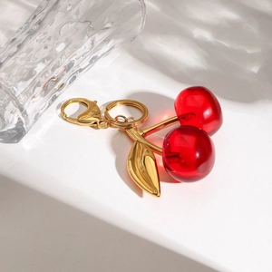 Detailaufnahme Kirsch-Anhänger mit goldenen Blättern und Karabiner auf weißer Stufe