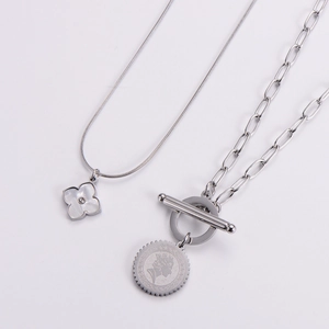 Silver titanium layered necklace featuring clover and coin charms with an OT toggle clasp
