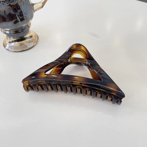 Detail of amber tortoiseshell hair claw clip with transparent gradient and metal spring