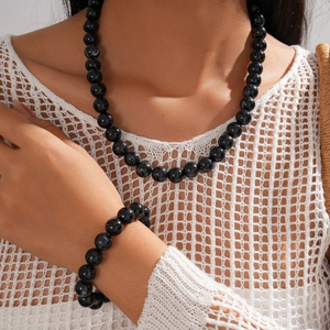 Detail of elegant black acrylic beaded necklace and bracelet set on a female model