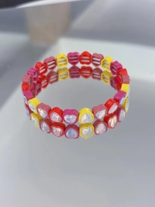 Close-up of vibrant enamel heart-shaped bracelet with iridescent stones on a mirror