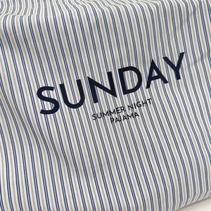 Detail of blue and white striped fabric with Sunday Summer Night Pajama print text