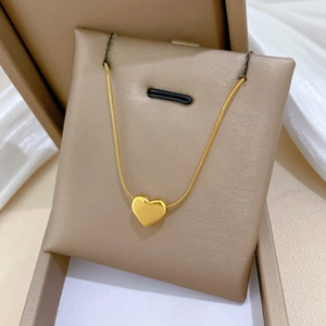 Detail of a gold heart pendant necklace on snake chain in a luxury jewelry box