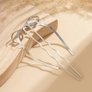 Detailed close-up of a silver metal U-shaped hair fork with an elegant bow texture