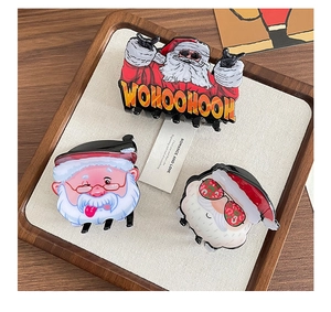 Detailed close-up of three festive Christmas Santa Claus hair claws in a wooden tray