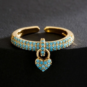 18K gold plated open heart ring with micro-paved blue zircons on a dark stone surface