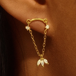 Close-up of gold curved bar earring with chain and marquise-cut gem pendant on ear