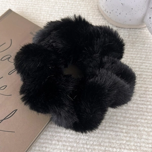 Close-up of a soft black faux mink plush scrunchie on a vintage aesthetic background
