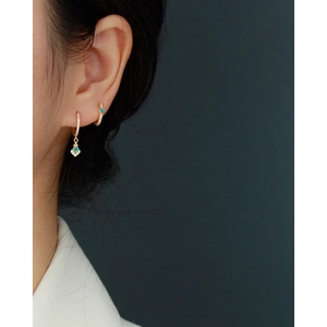 Close-up of gold earrings with green opal and diamonds worn by a model in profile