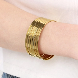 Detail view of multiple stacked minimalist gold titanium steel bangles on a wrist
