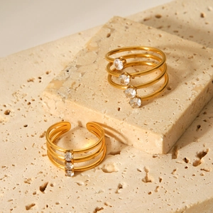 Minimalistischer Goldener Edelstahlring im Lagenlook mit Zirkonia auf Stein-Hintergrund
