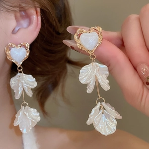 Detail of elegant white heart and layered petal drop earrings with gold trim
