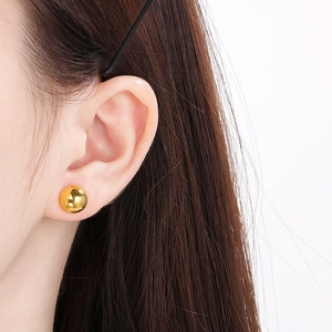 Close-up of minimalist gold ball stud earring worn on ear for size and texture reference