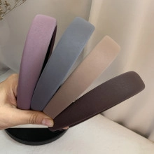 Close-up of four wide headbands in purple, blue, beige, and brown with matte fabric texture