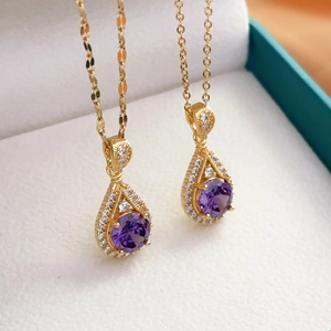 Golden teardrop necklaces with amethyst pendants and small clear crystals in a jewelry box