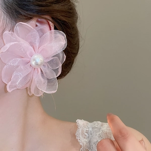 Close-up of pink chiffon flower earring with large white pearl on model's ear