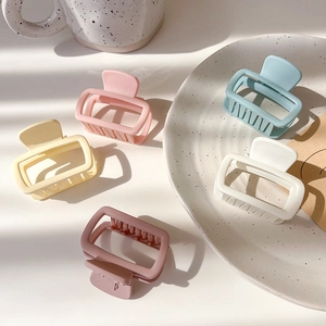 Flat lay of small matte rectangular hair claws in cream, pink, blue and white colors