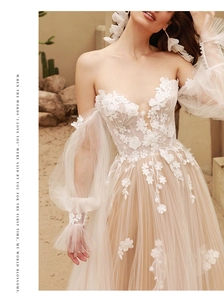 Close-up of champagne lace wedding dress with 3D floral appliques and puff tulle sleeves