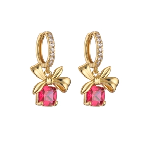 Detailed close-up of gold bow earrings with square-cut red zircon stones on white background